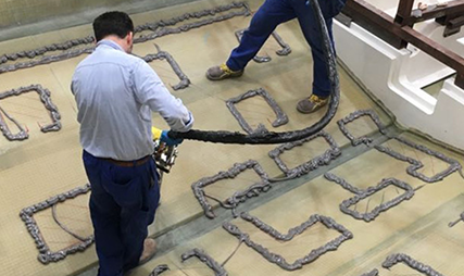 Worker applying beads of adhesive in a grid pattern on a boat deck
