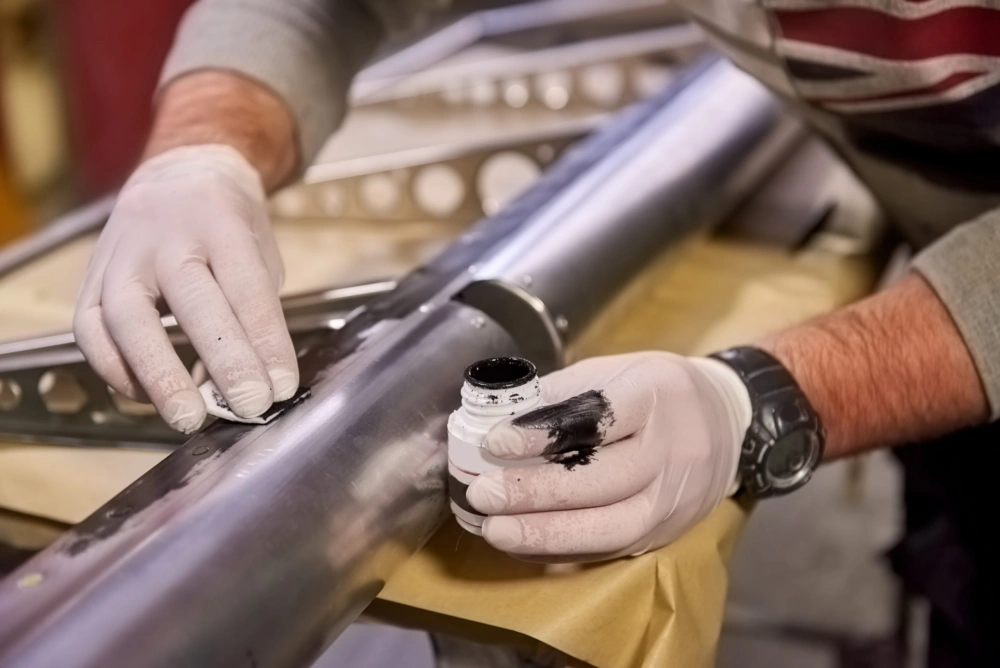 Gloved hand applying primer to a stainless steel tube