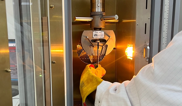 Gloved technician removing a heated test sample from a laboratory oven