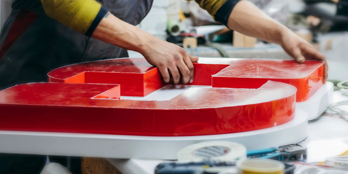 Worker assembling large red plastic display letters