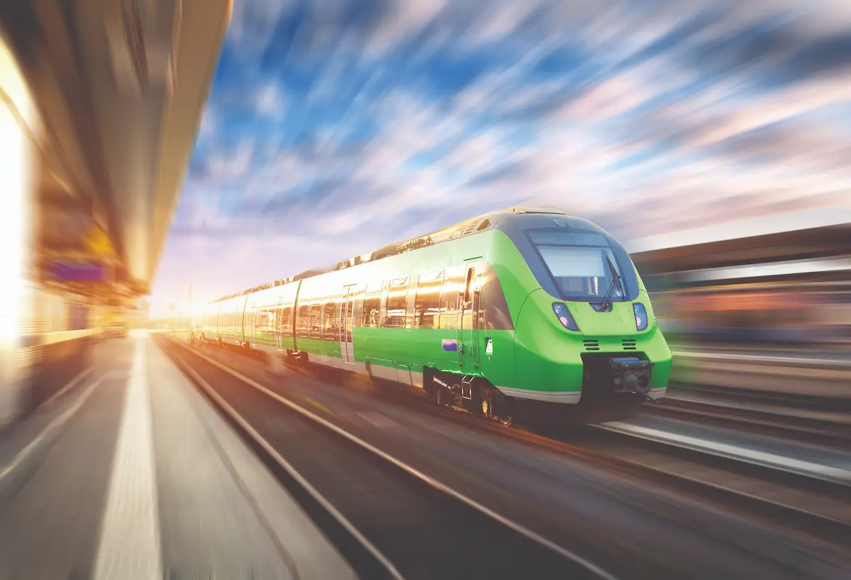 Green and white train travelling at speed, with motion blur