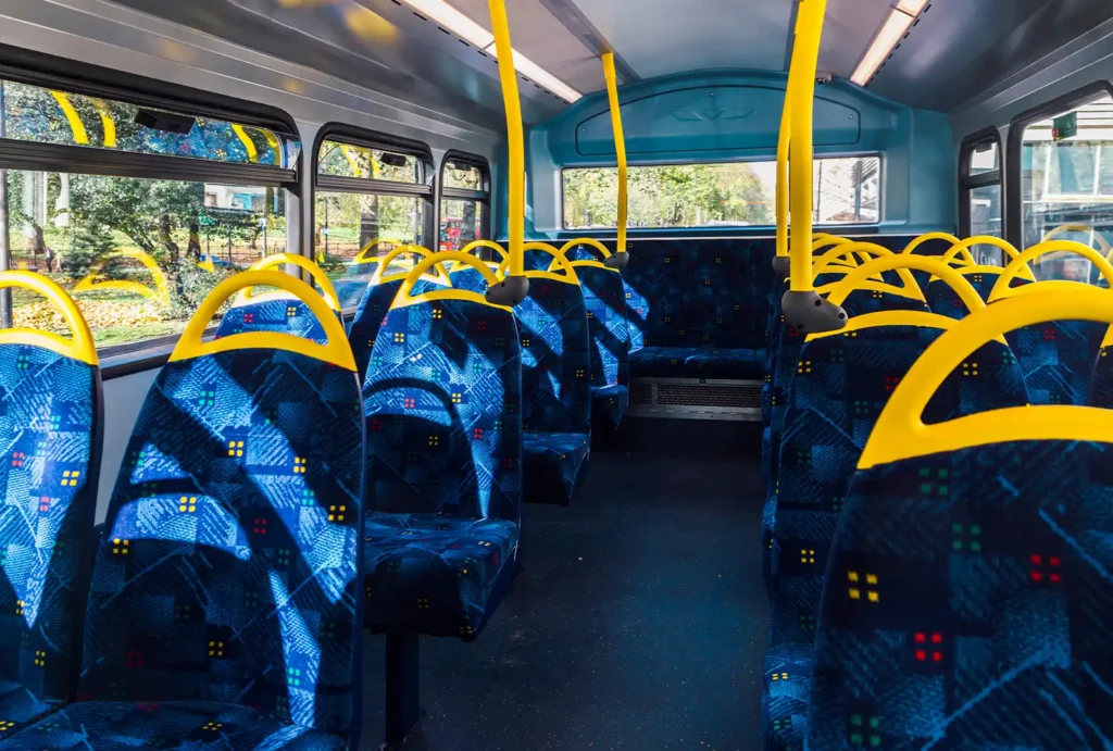 Bus interior with blue seats and yellow grab rails