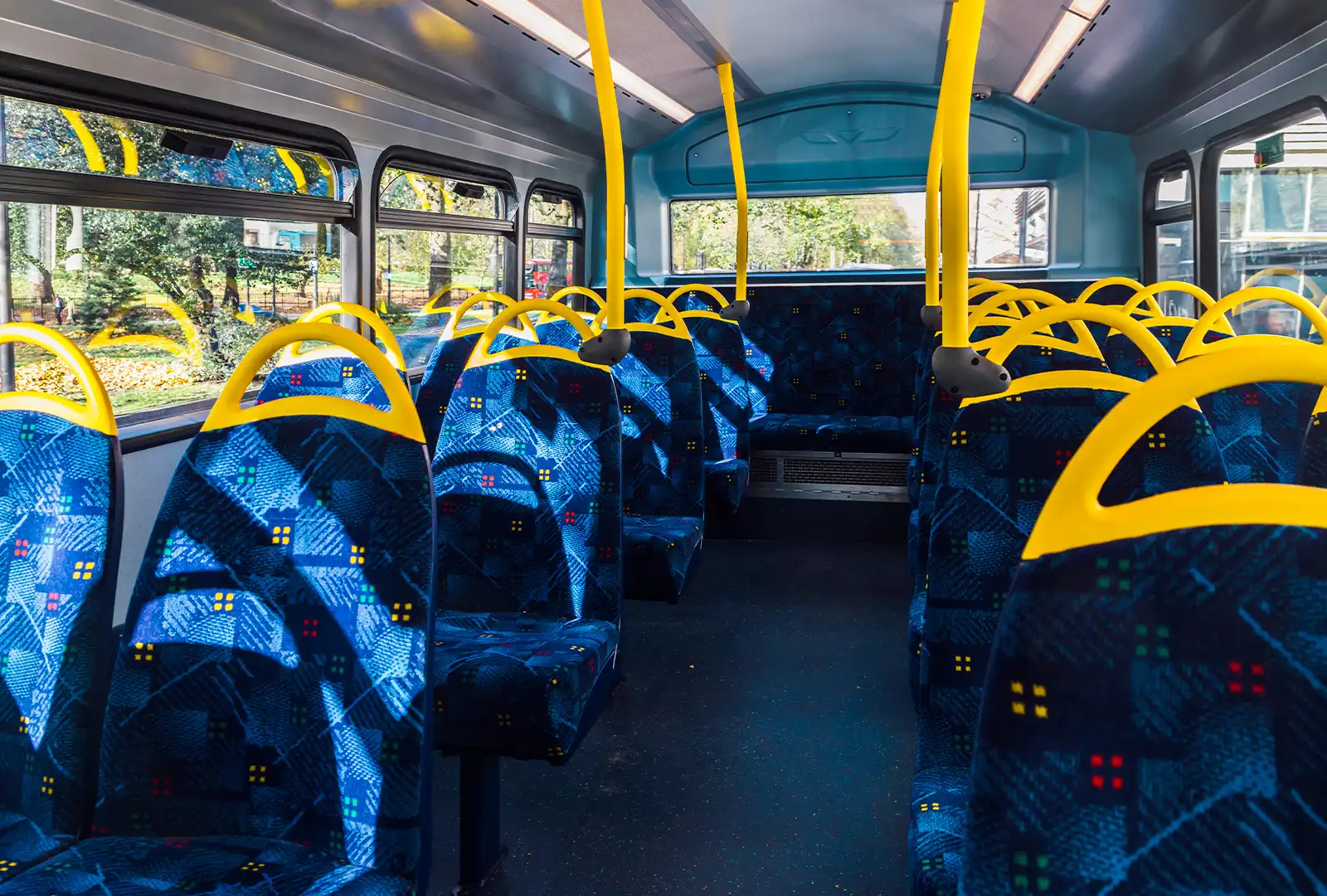 Bus interior with blue seats and yellow grab rails