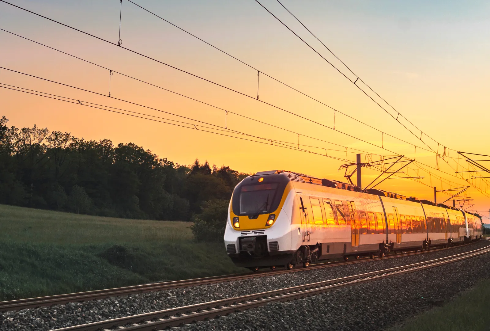 Passenger train travelling through countryside at sunset