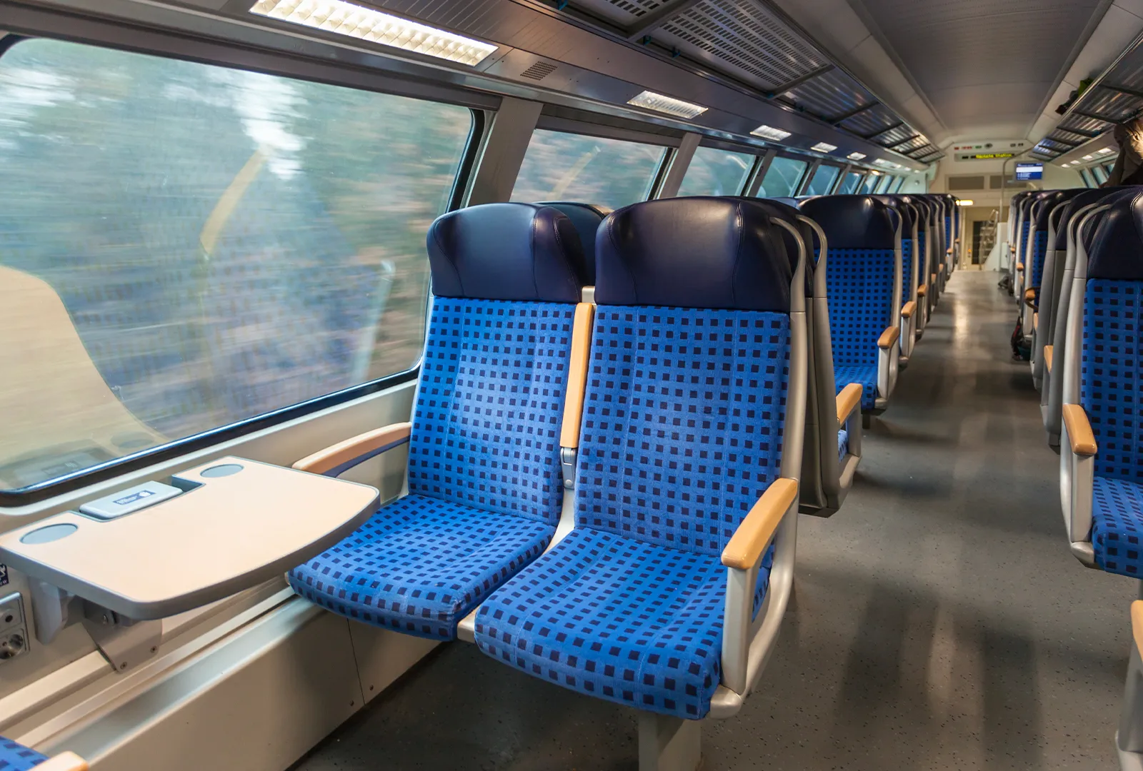 Interior of a train carriage with blue seats and tables