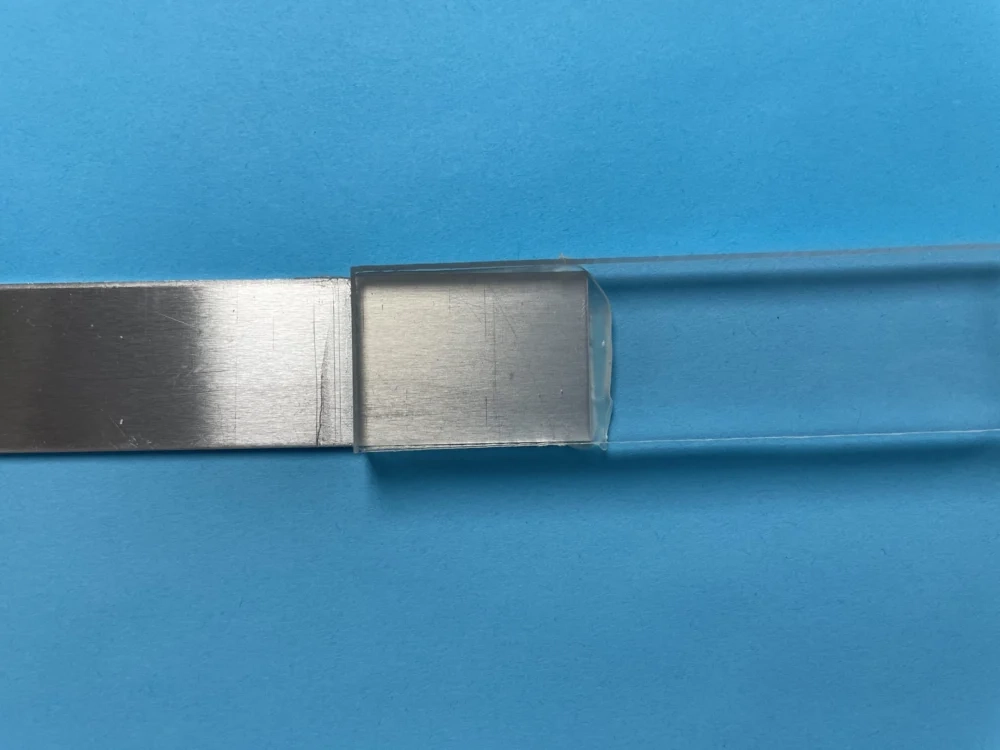 Two metal sections bonded end to end on a blue background