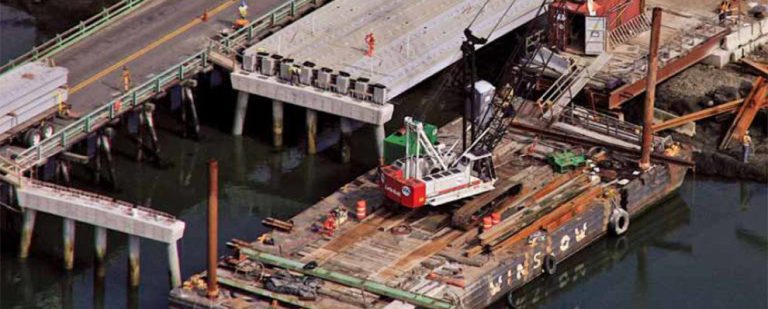 Composite bridge beams being installed over water