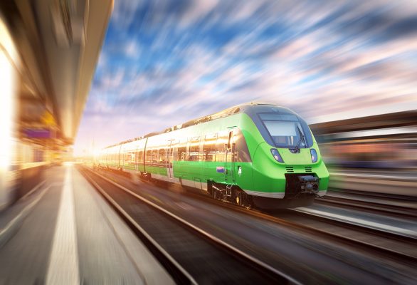 HighspeedtraininmotionattherailwaystationatsunsetinEurope.Beautifulgreenmoderntrainontherailwayplatformwithmotionblureffe